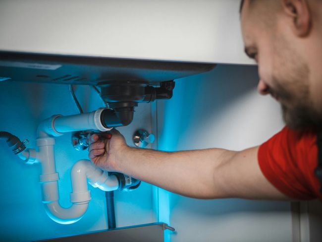 A plumber tightening pipes.