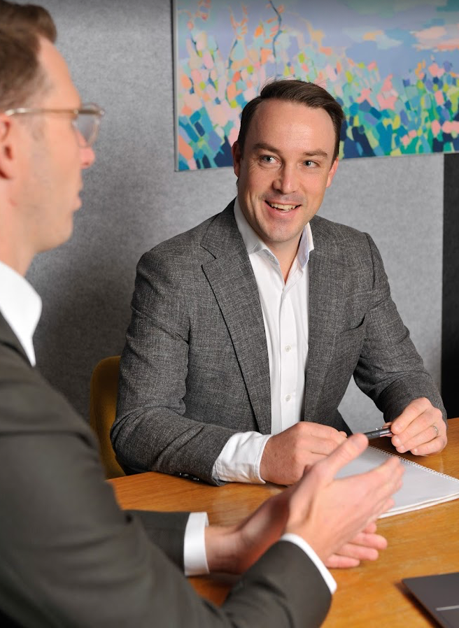 A man in a suit and tie is smiling for the camera.