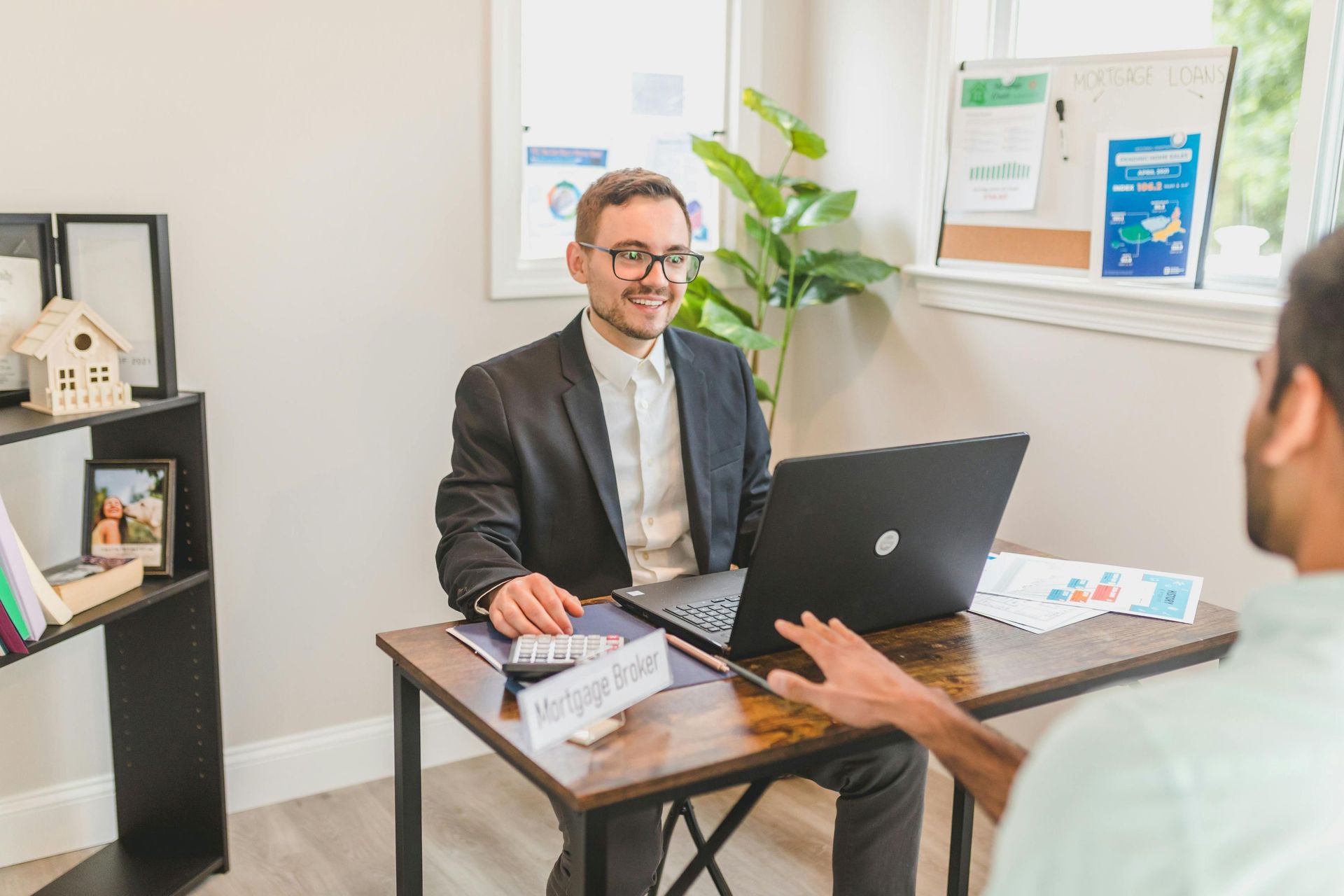 A male broker sitting across a desk from a male client.