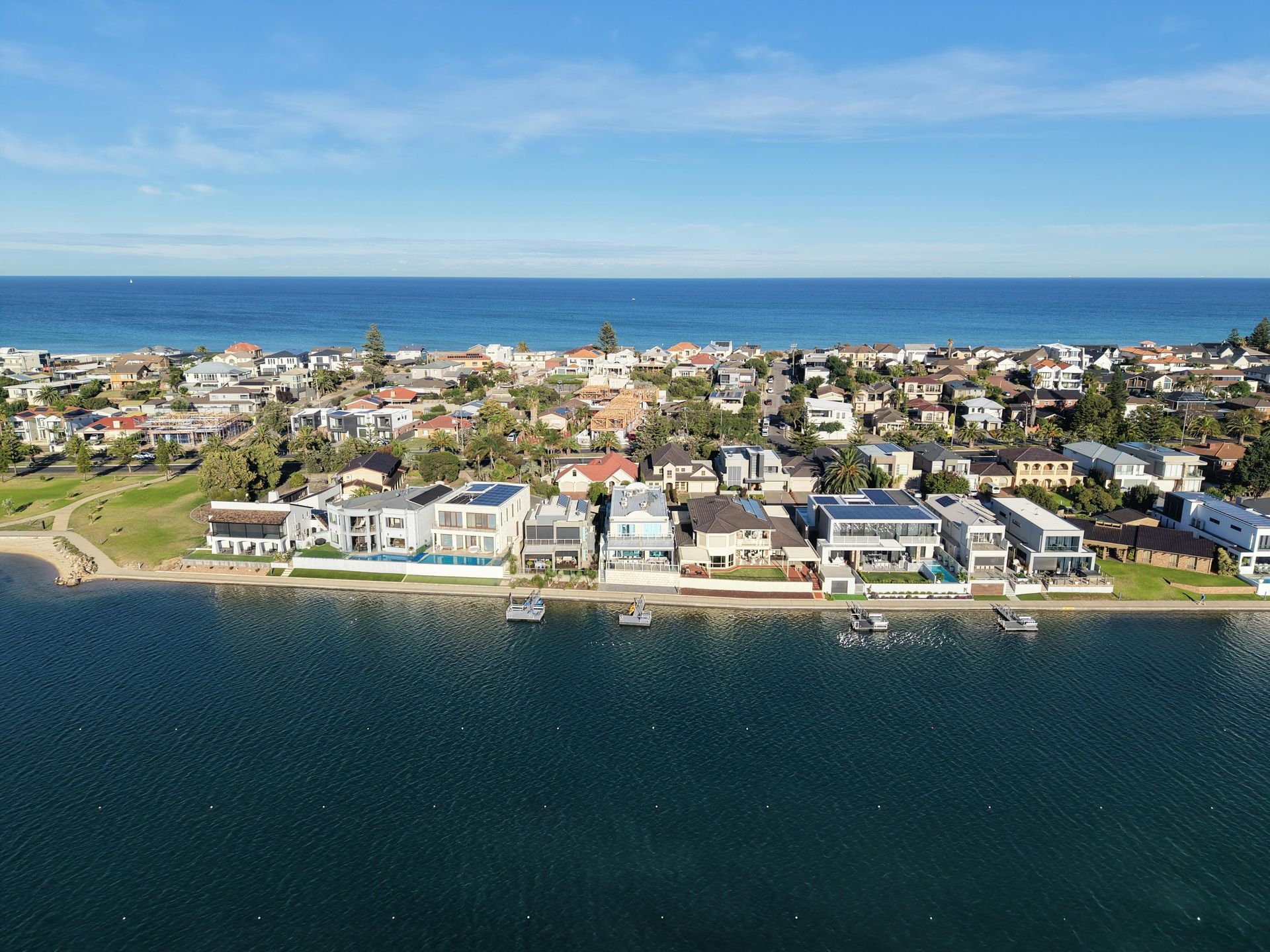 Aerial view of waterfront homes along a calm blue bay under a clear sky