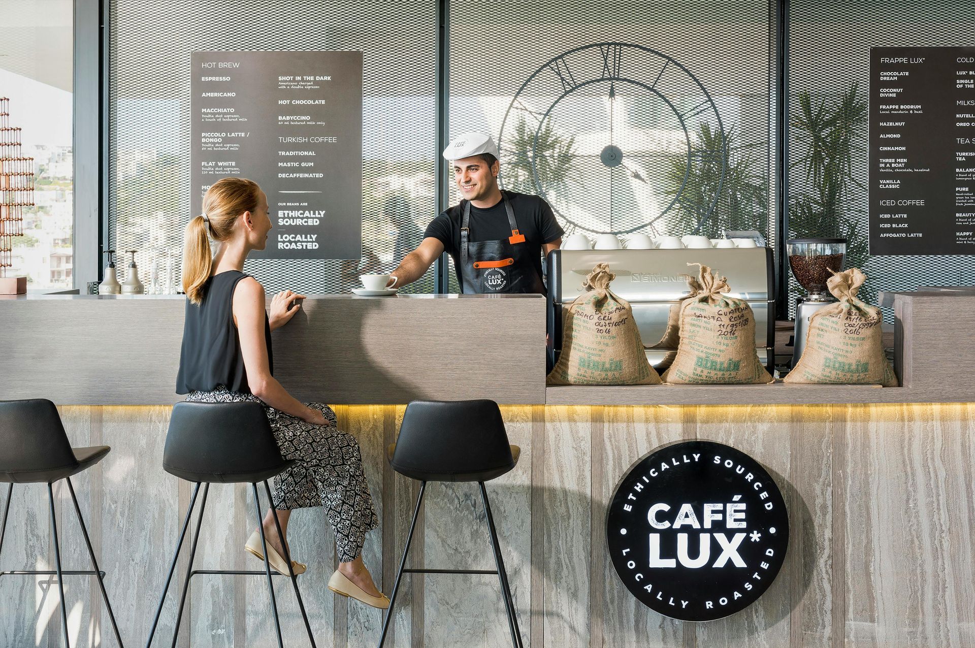 A male barista serving coffee to a female customer.
