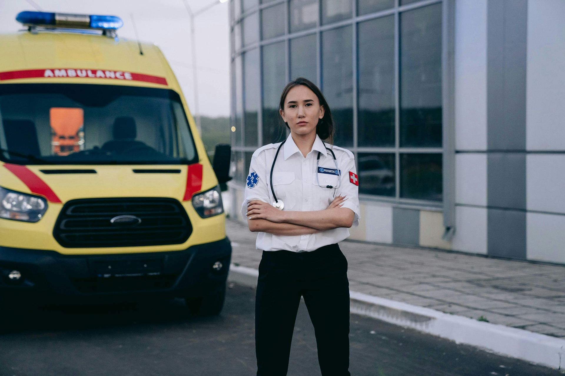 A female paramedic standing in front of ambulance.