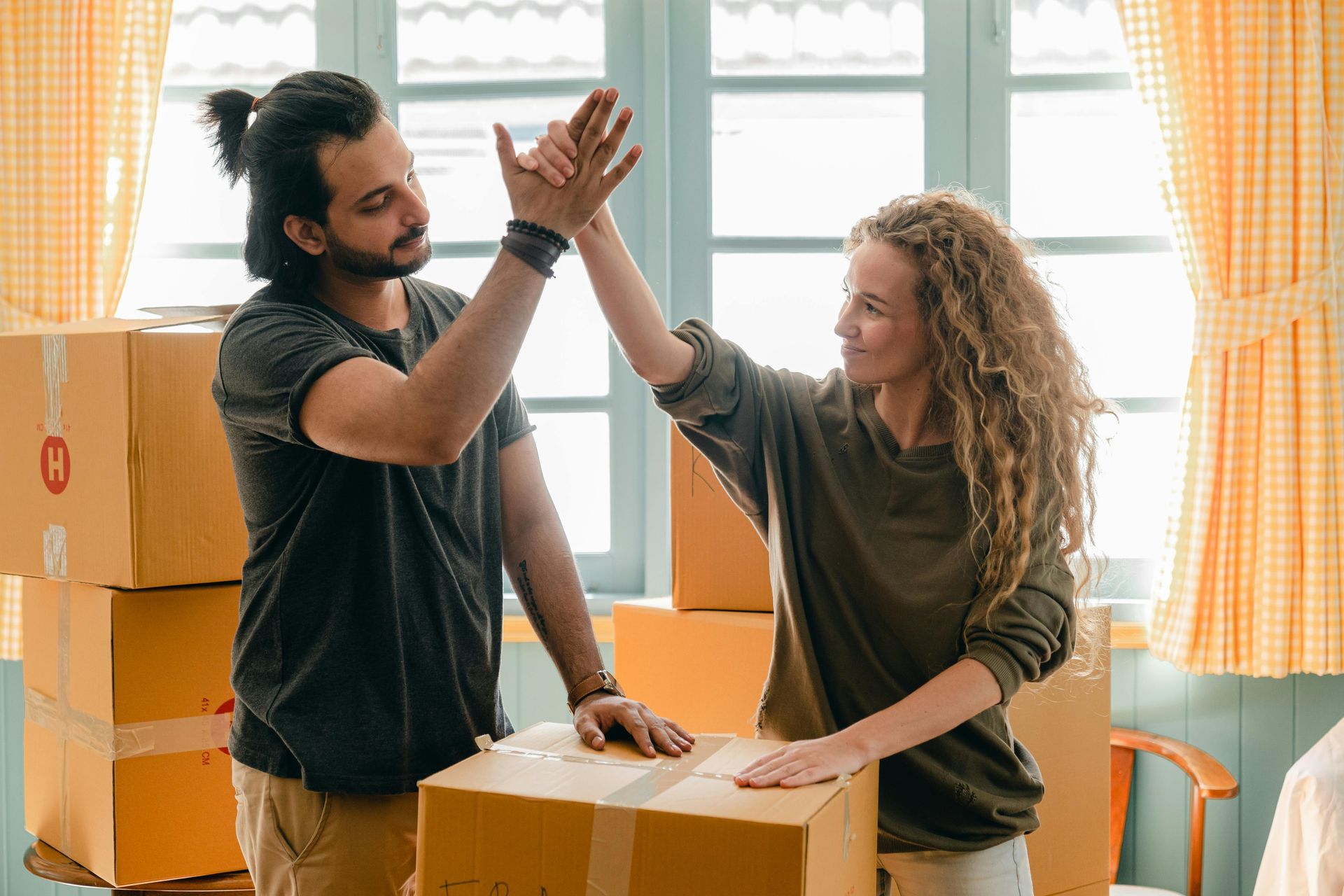 A couple giving each other high fives, surrounded by house moving boxes.