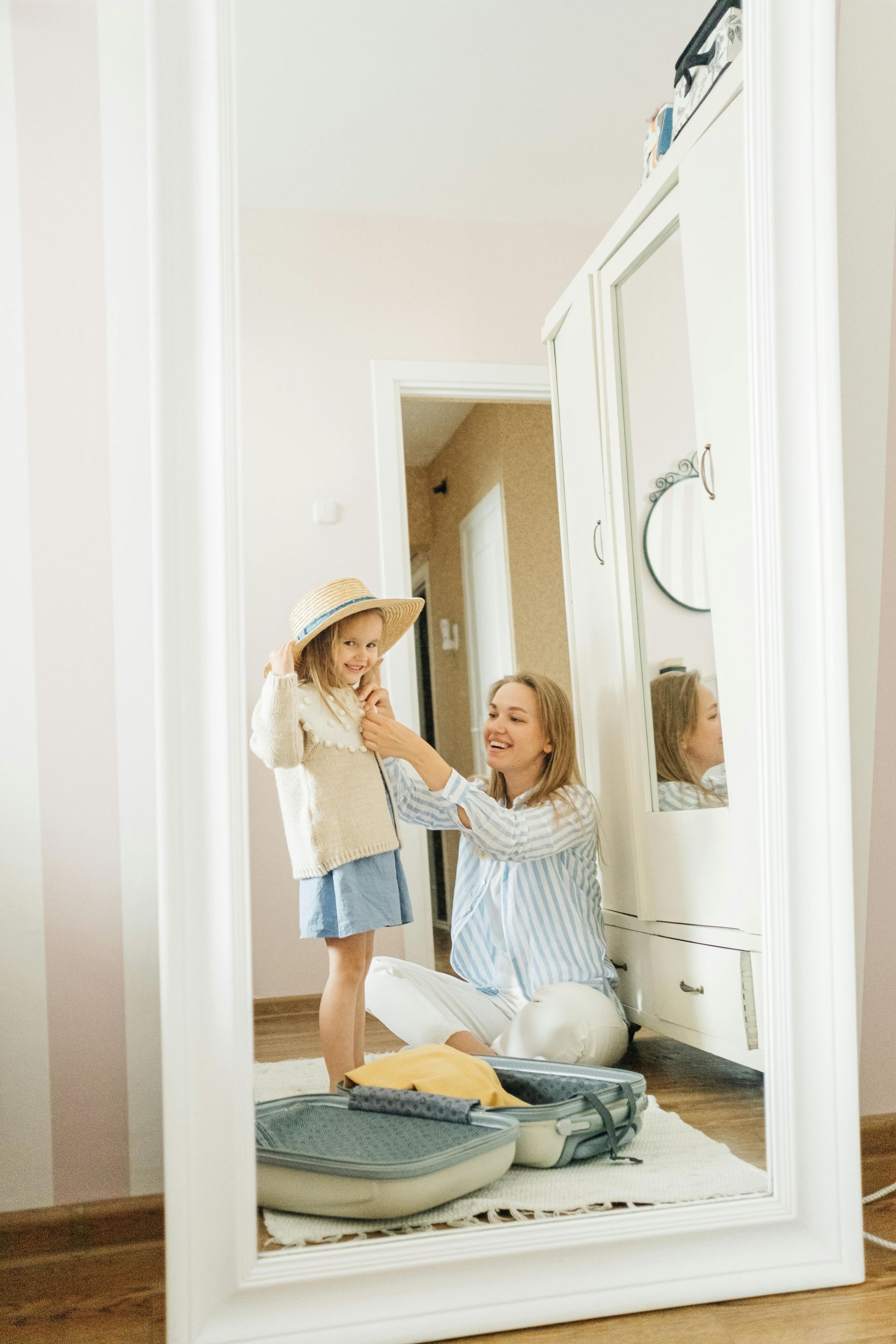 A mother fixing her daughter in front of a mirror.