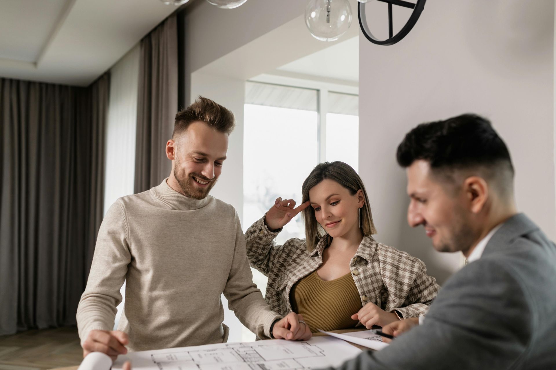 Three people reviewing plans at a table in a bright office