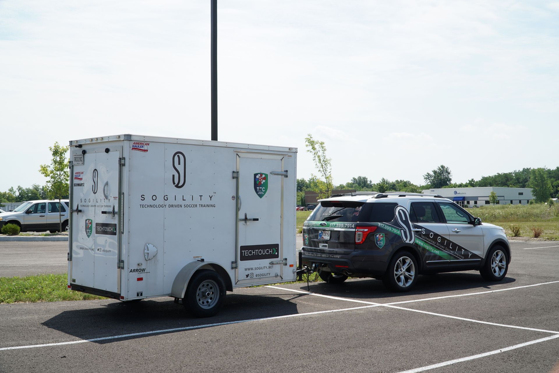 A car is towing a trailer in a parking lot.