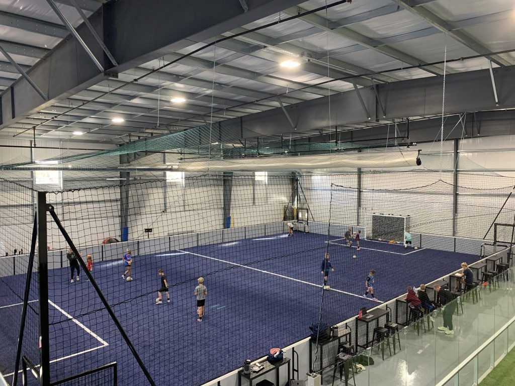 A group of people are playing volleyball in an indoor gym.