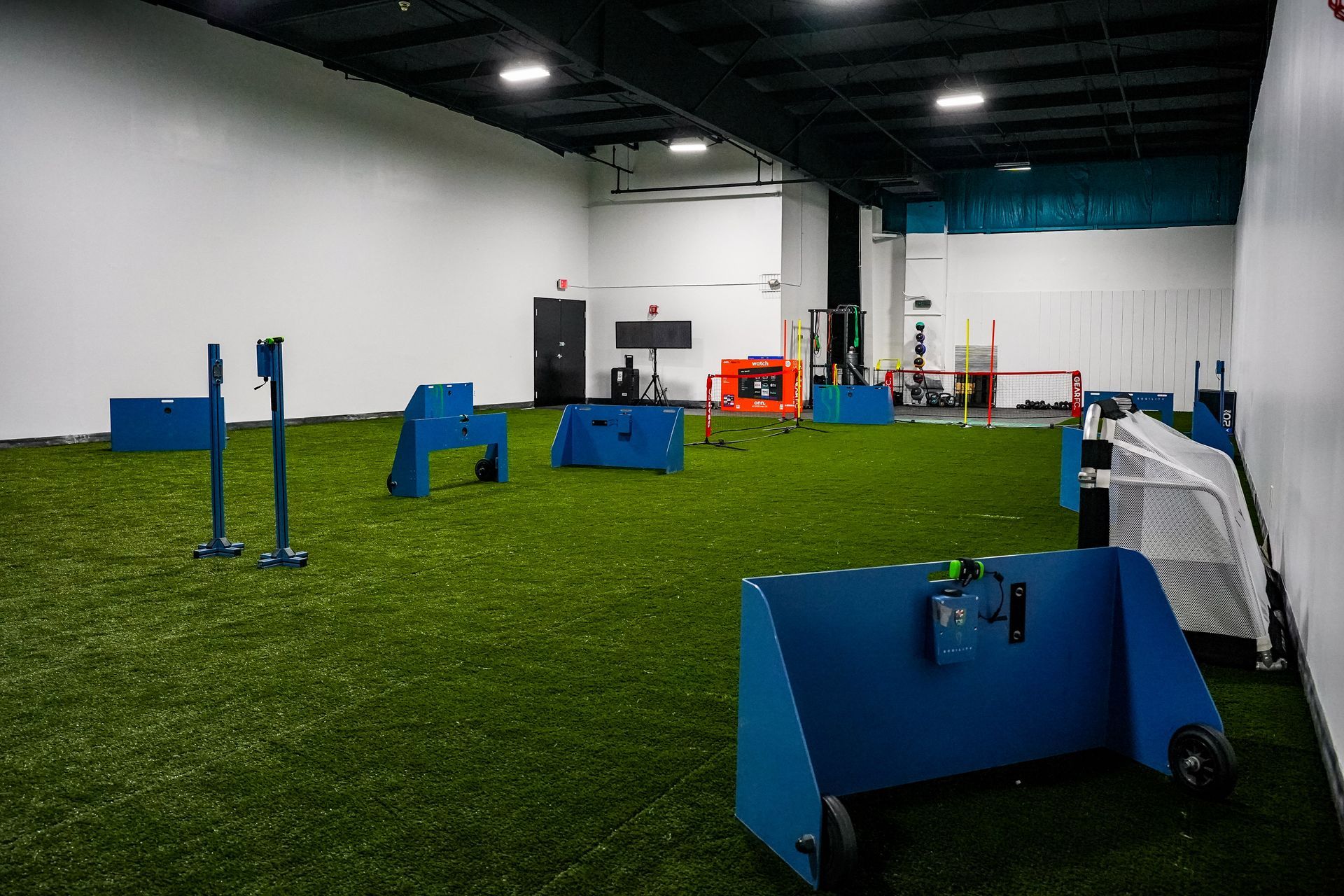 A large room with a lot of green grass and blue barriers.