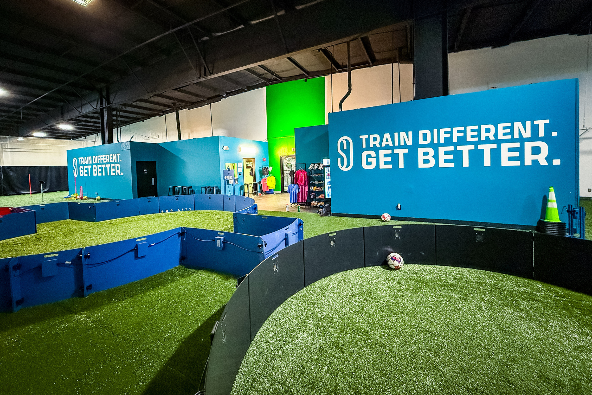 A large room with a lot of green grass and blue barriers.