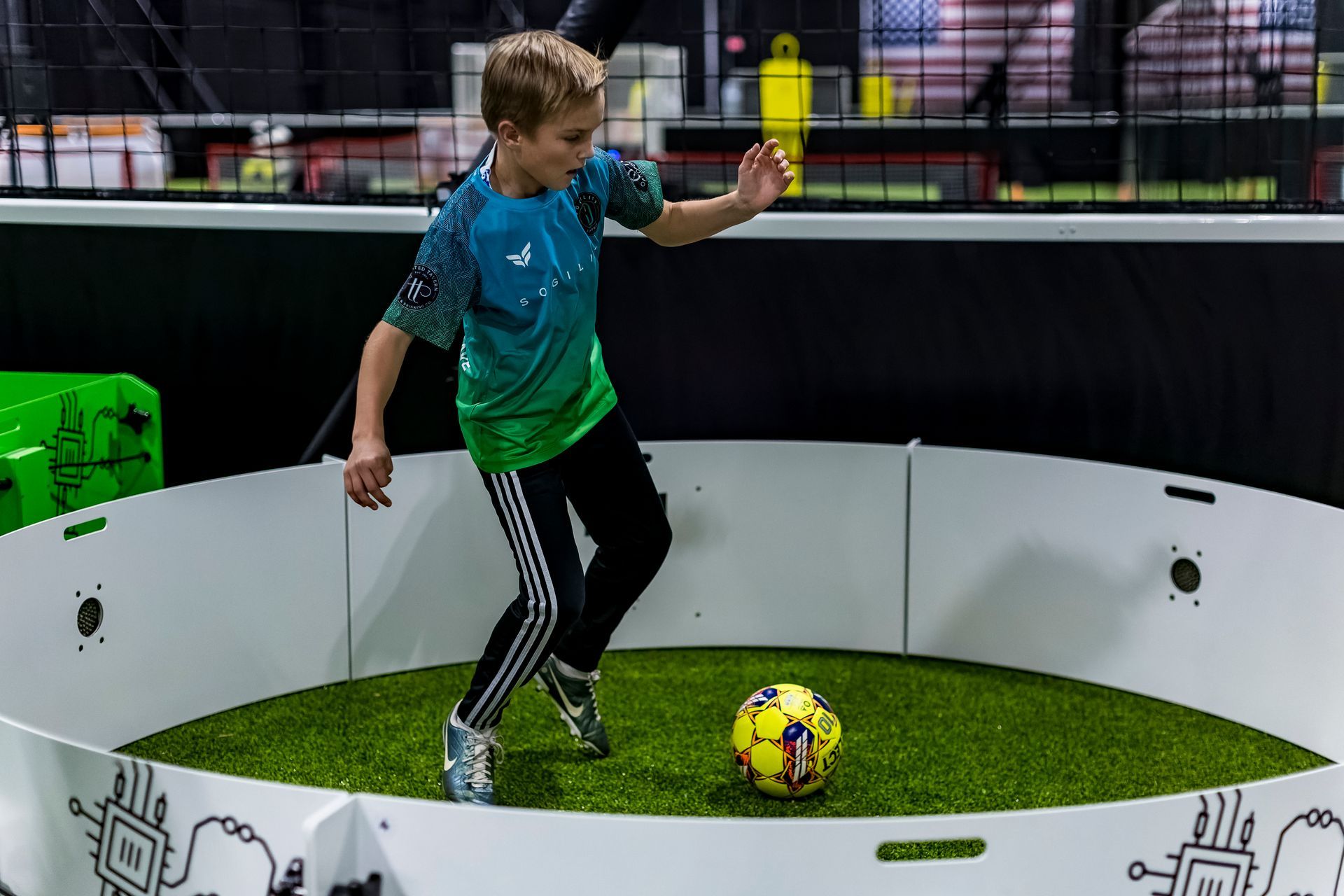 A young boy is kicking a soccer ball in a circle.