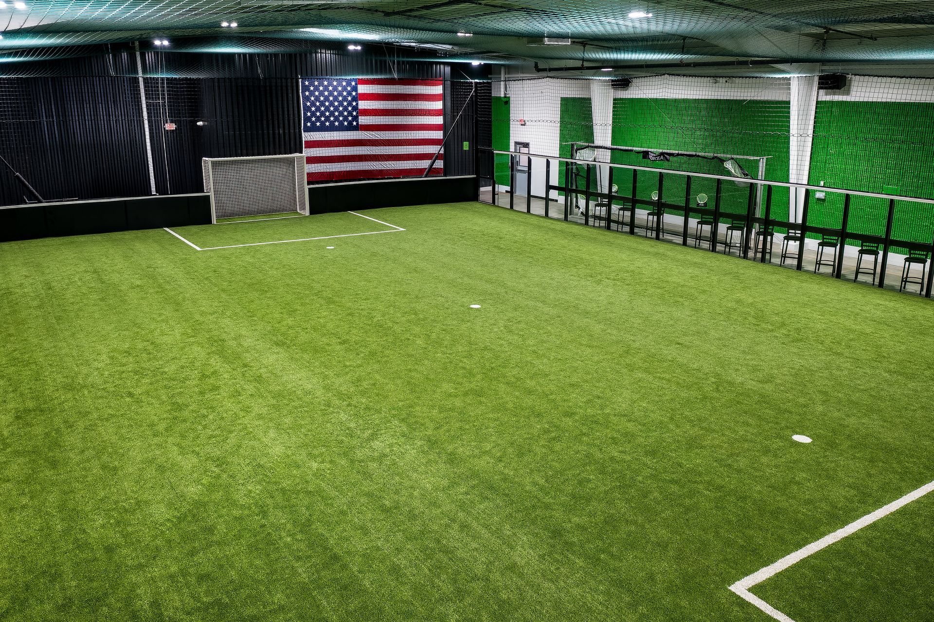 A large indoor soccer field with an american flag in the background.