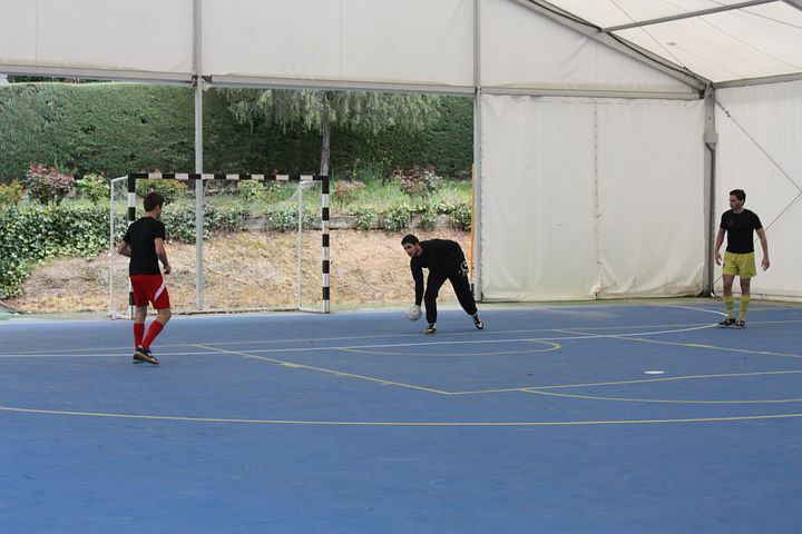 A group of people are playing soccer under a white tent.