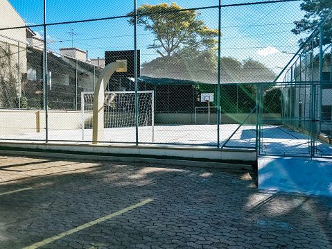 A basketball court behind a chain link fence with a basketball hoop.