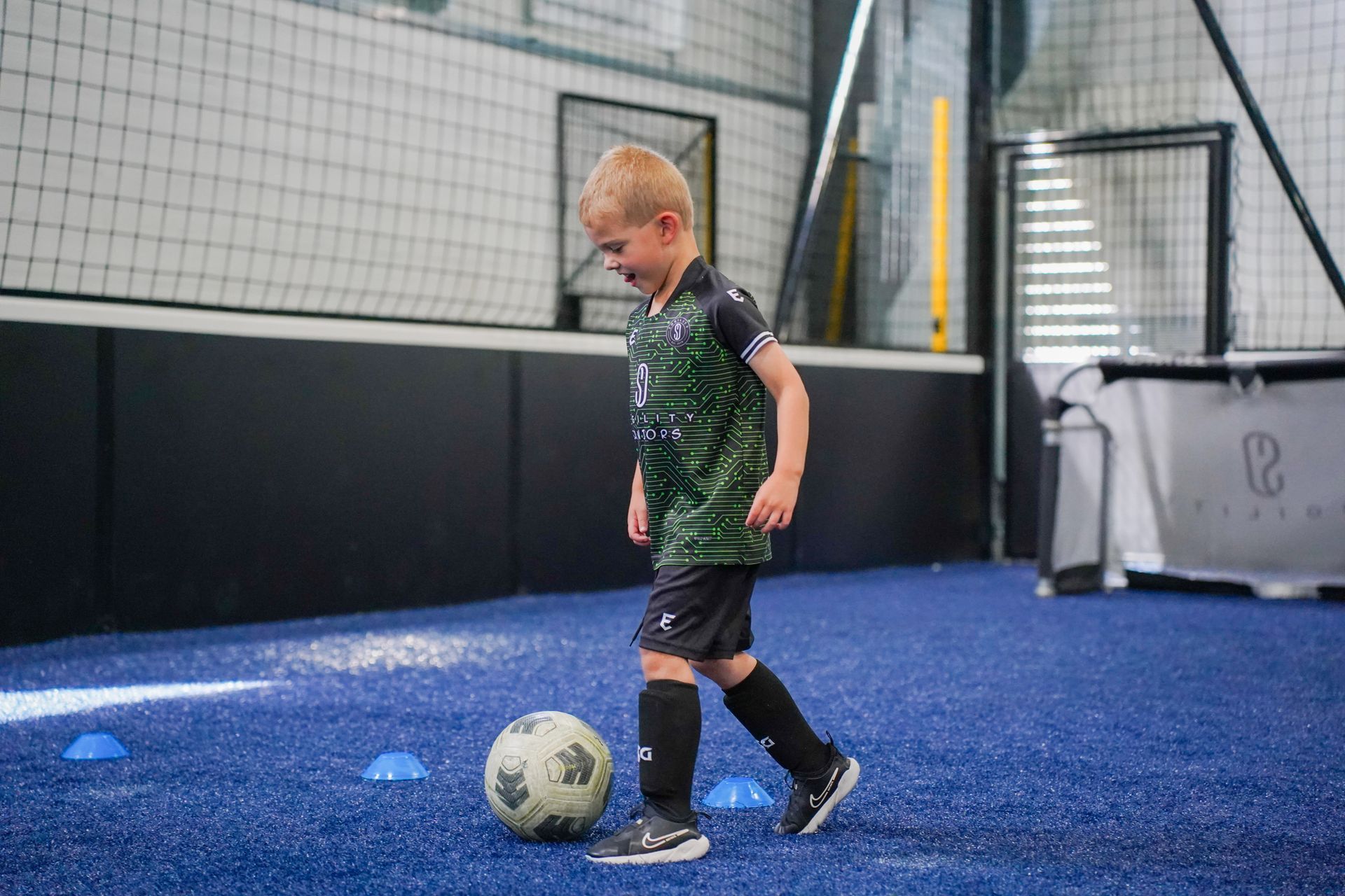 A young boy is kicking a soccer ball on a field.