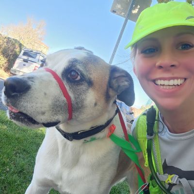 Katie O smiling and taking a selfie with a dog.