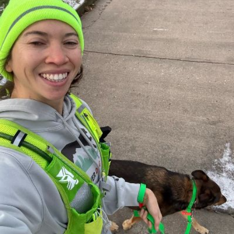 Marley is smiling while holding a dog on a leash.