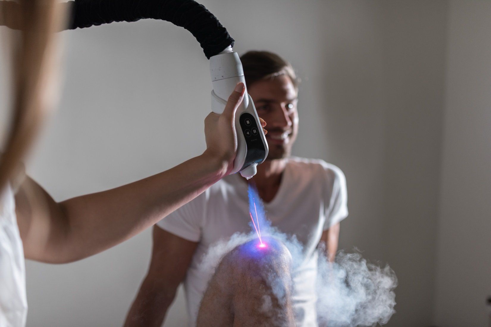 A man smiling as he receives a pain-relieving cryotherapy spot treatment on his knee