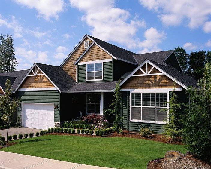 A green and brown house with a white garage door