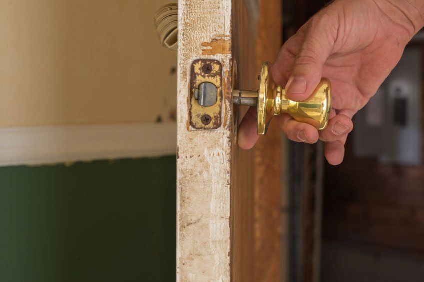 A person is opening a door with a brass door handle.
