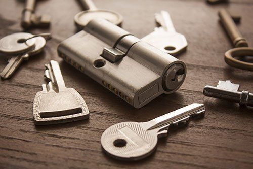 A bunch of keys and a lock on a wooden table.