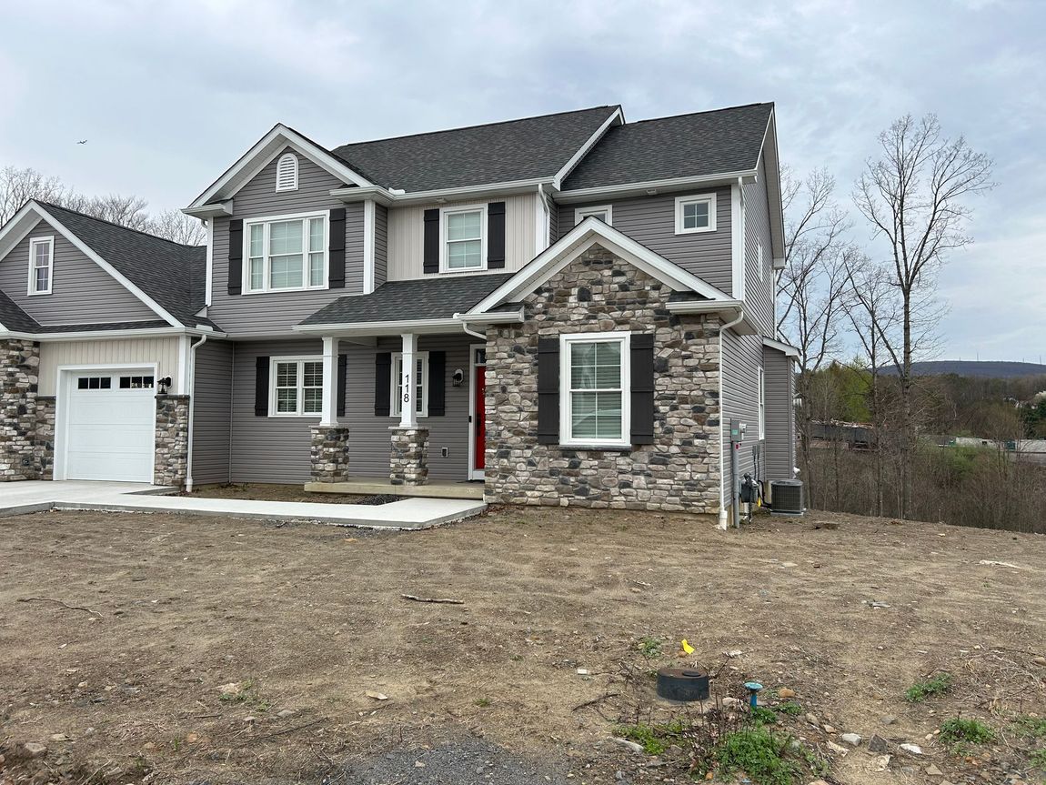 A large house is sitting on top of a dirt hill.