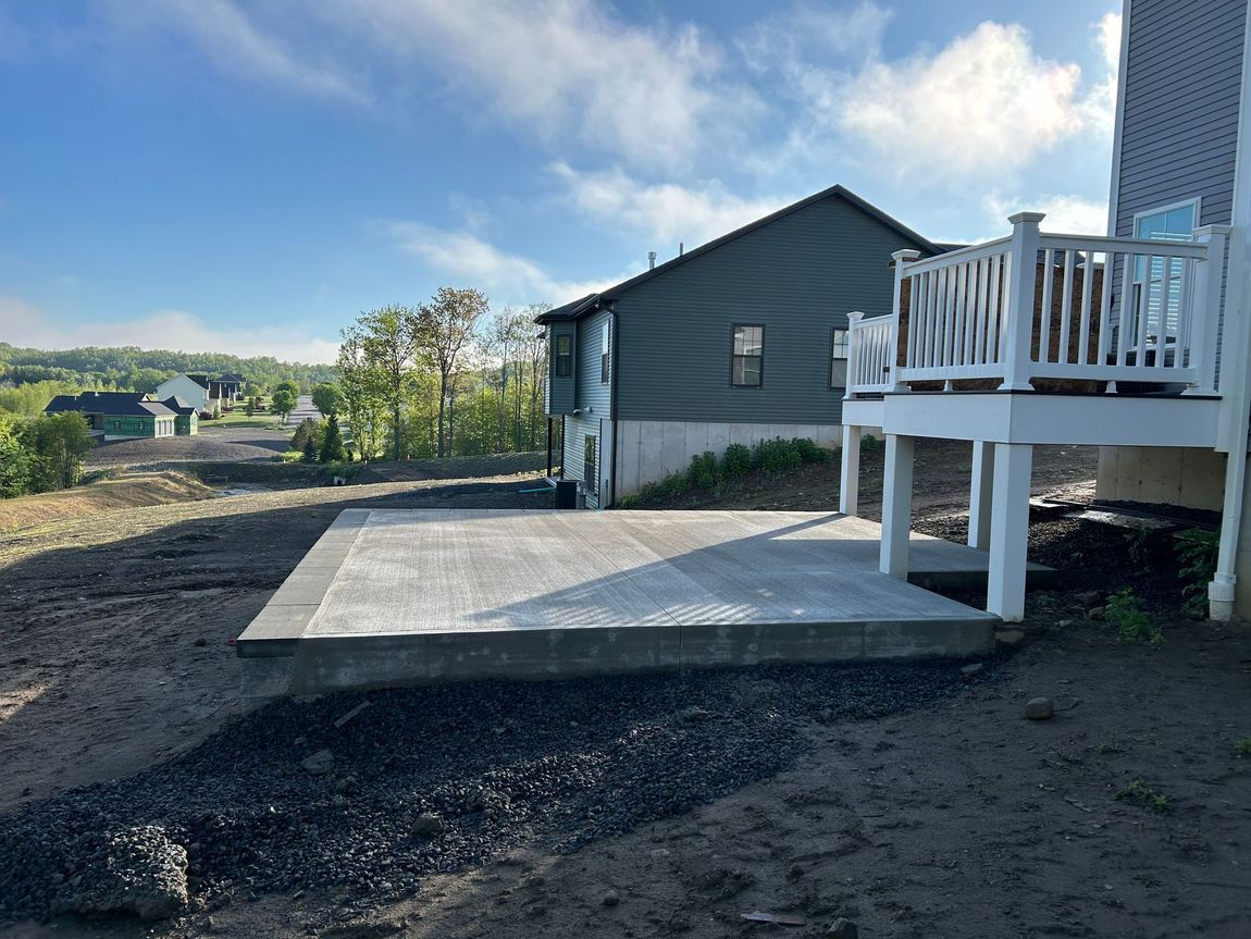 A concrete patio with a white deck in front of a house.