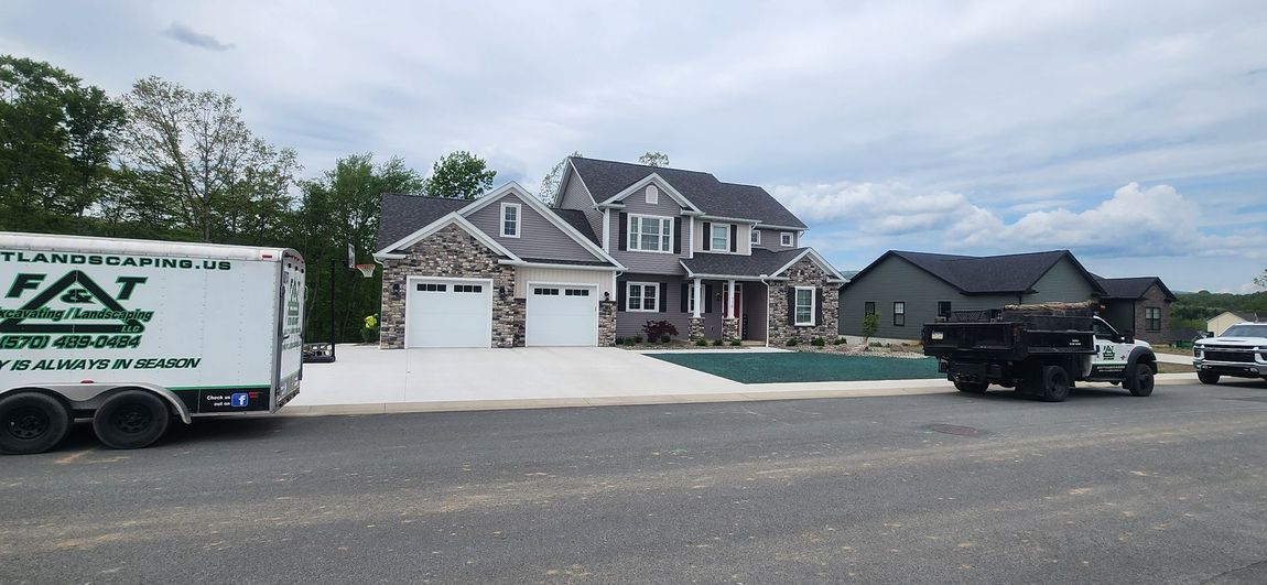 A white trailer is parked in front of a large house.