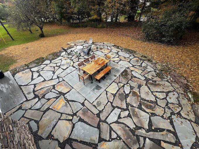 An aerial view of a stone patio with a wooden table and chairs.