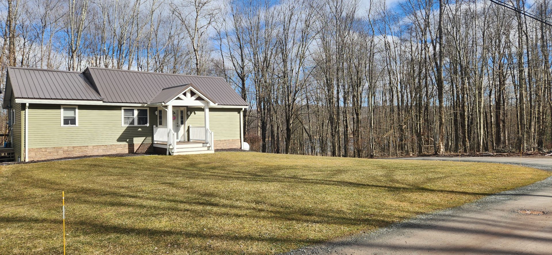 A house is sitting on top of a lush green field in the middle of a forest.