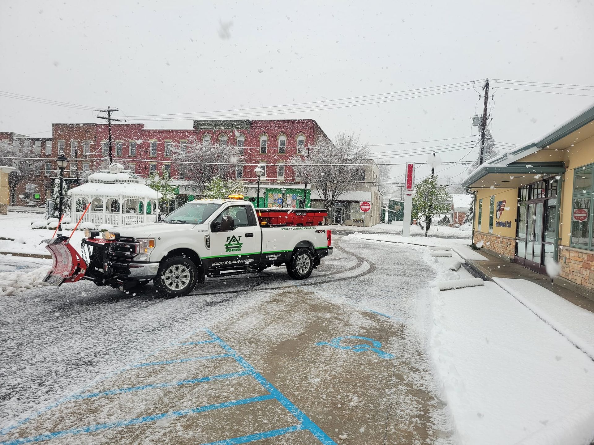 A snow plow is plowing snow in a parking lot.