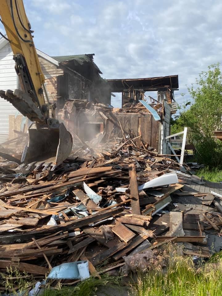 A house is being demolished by an excavator.