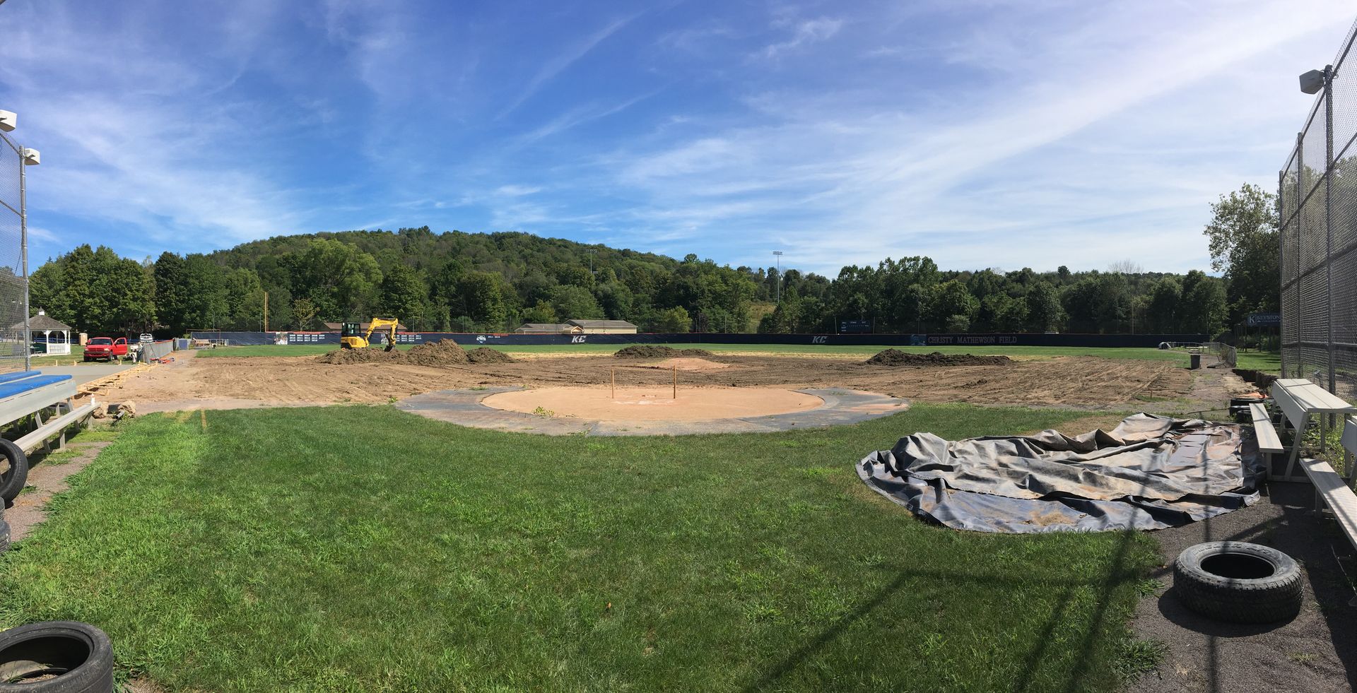 A panoramic view of a baseball field with a tire in the foreground.