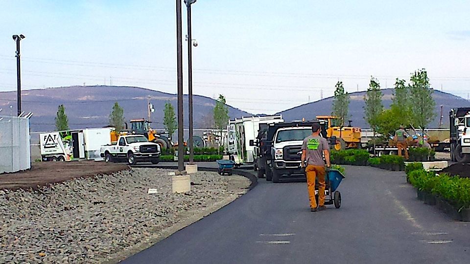 A man is pushing a wheelbarrow down a road.