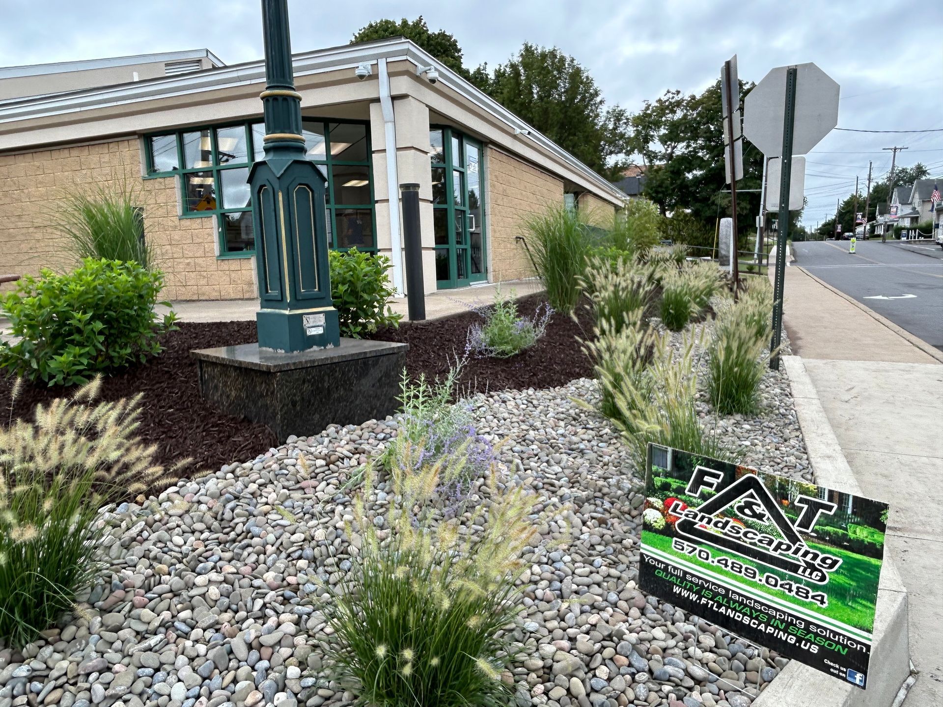 A sign is sitting on the side of the road in front of a building.