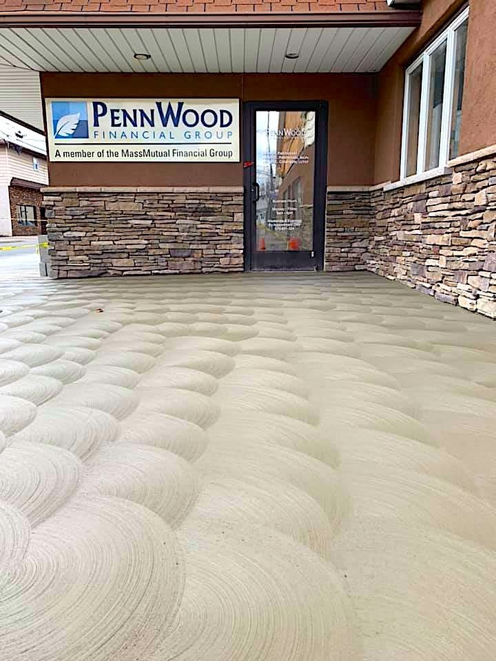 A large concrete floor in front of a building with a sign that says pennwood financial group.