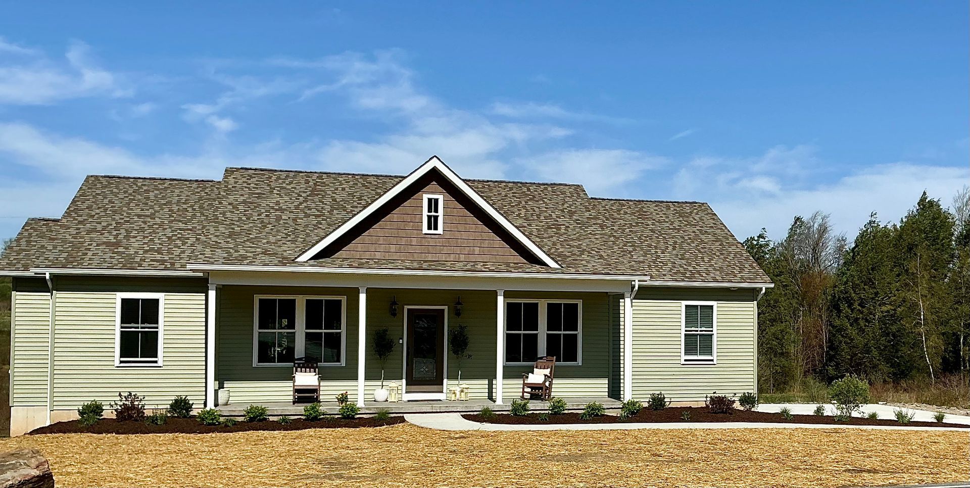 A beautiful new full yard installed with shrubs, flowering plants, mulch and driveway.