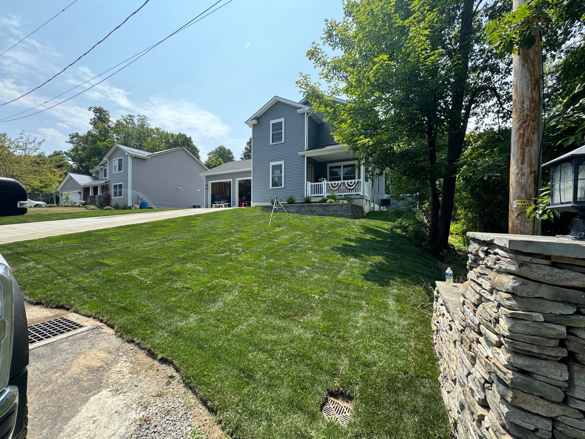 A car is parked in front of a house with a lush green lawn.