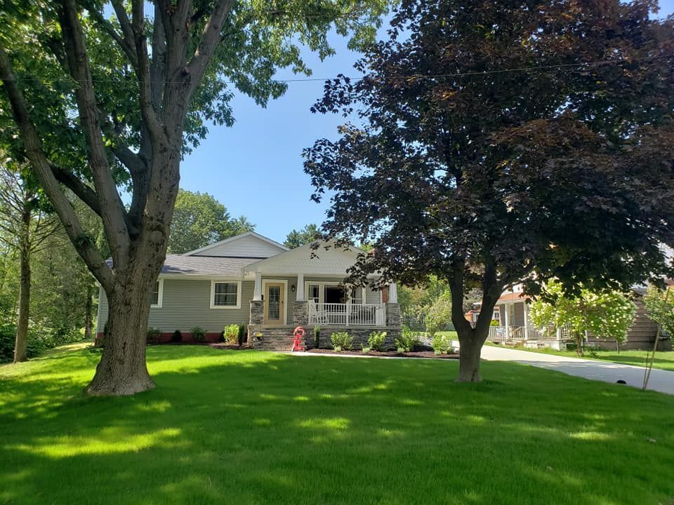 A house with a lush green lawn and trees in front of it