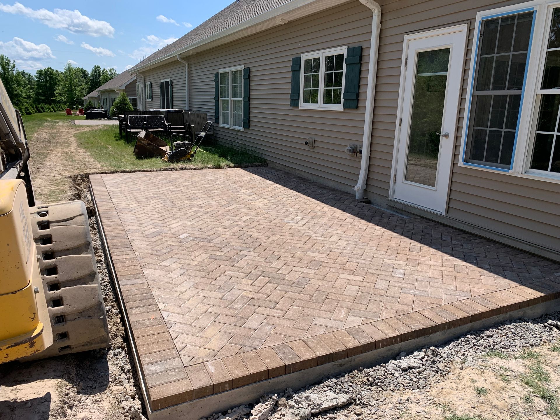 A large brick patio is being built in front of a house.