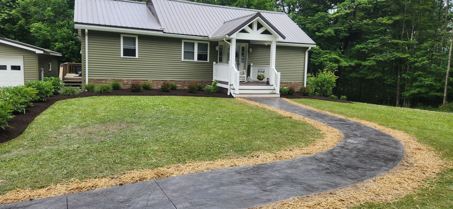 A house with a driveway leading to it and a lush green lawn.