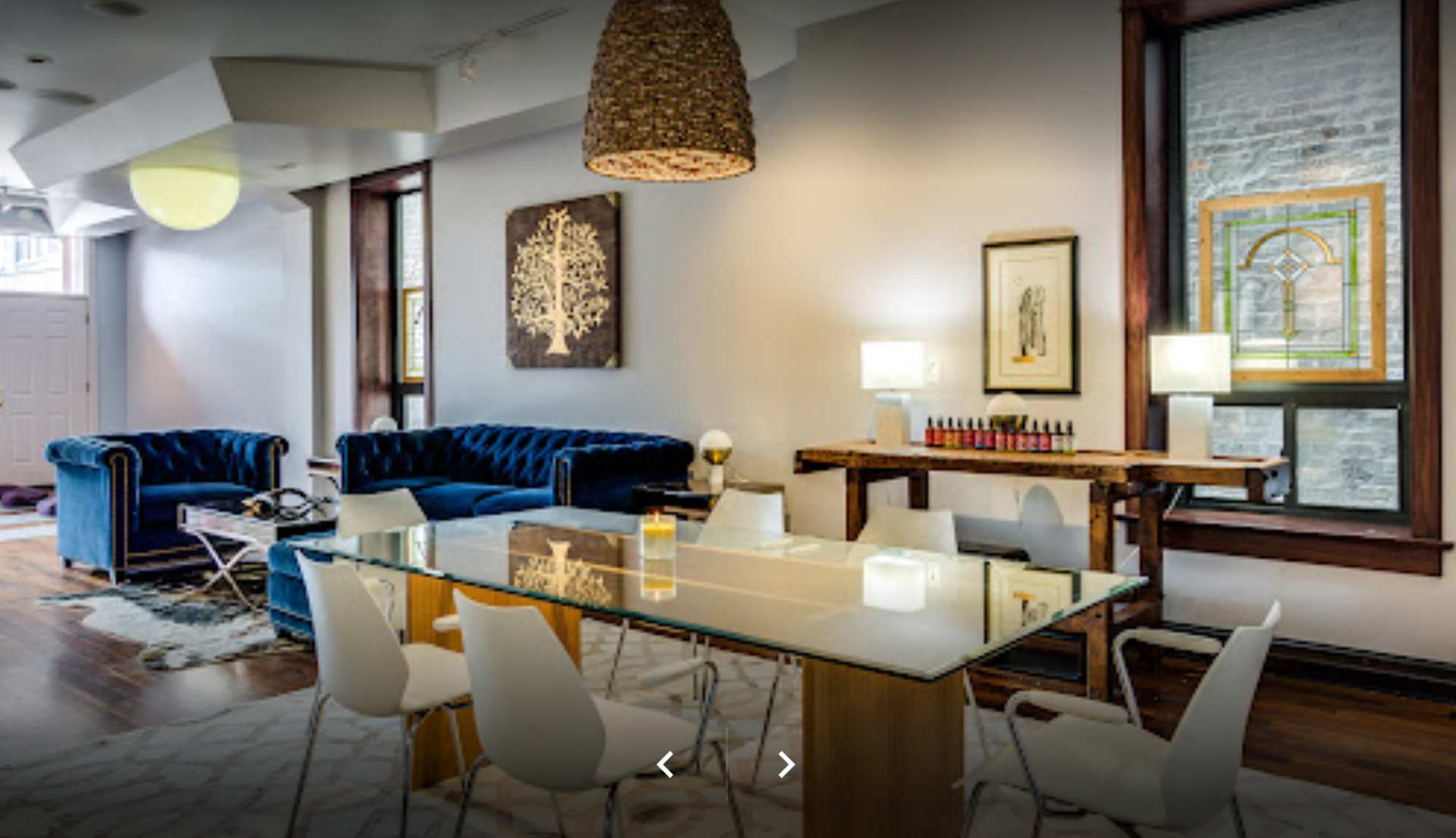 An open-concept living space with blue sofas, modern dining table, and natural light.
