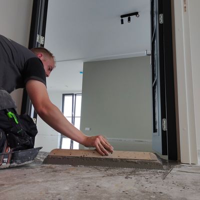 Een man werkt op een betonnen vloer in een kamer
