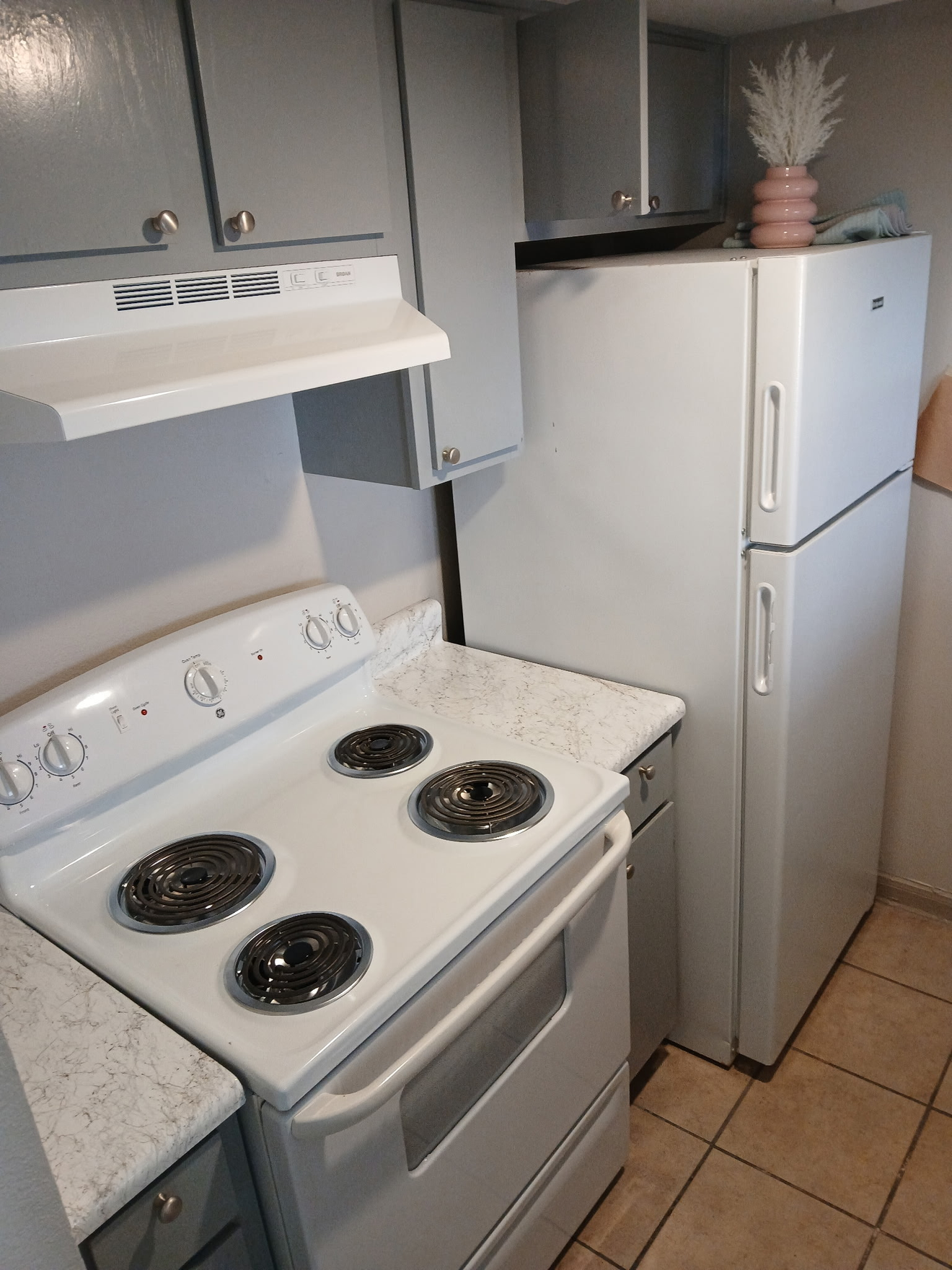 A kitchen with a stove , refrigerator , and cabinets.