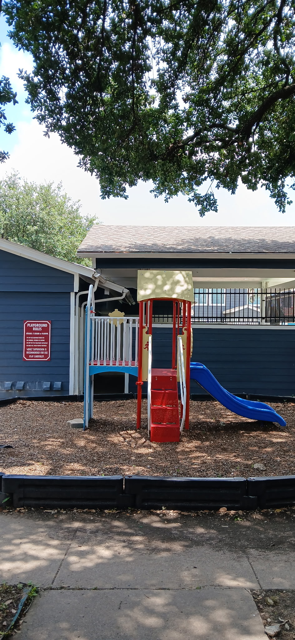 A playground with a slide and stairs in front of a house.