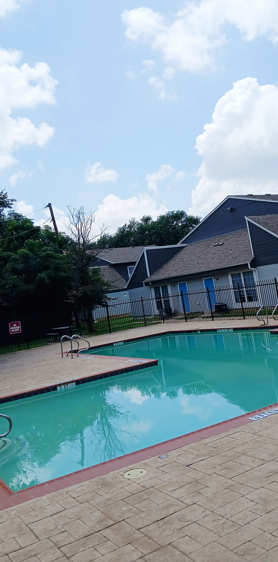 A large swimming pool in front of a house on a sunny day.