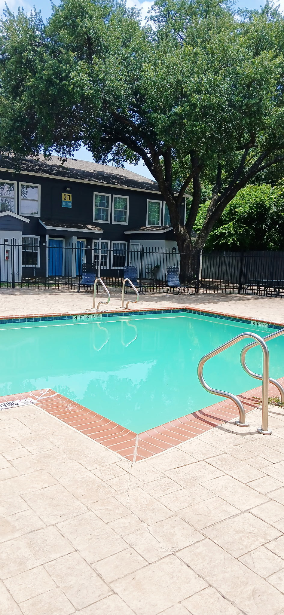A large swimming pool in front of a building with trees in the background.