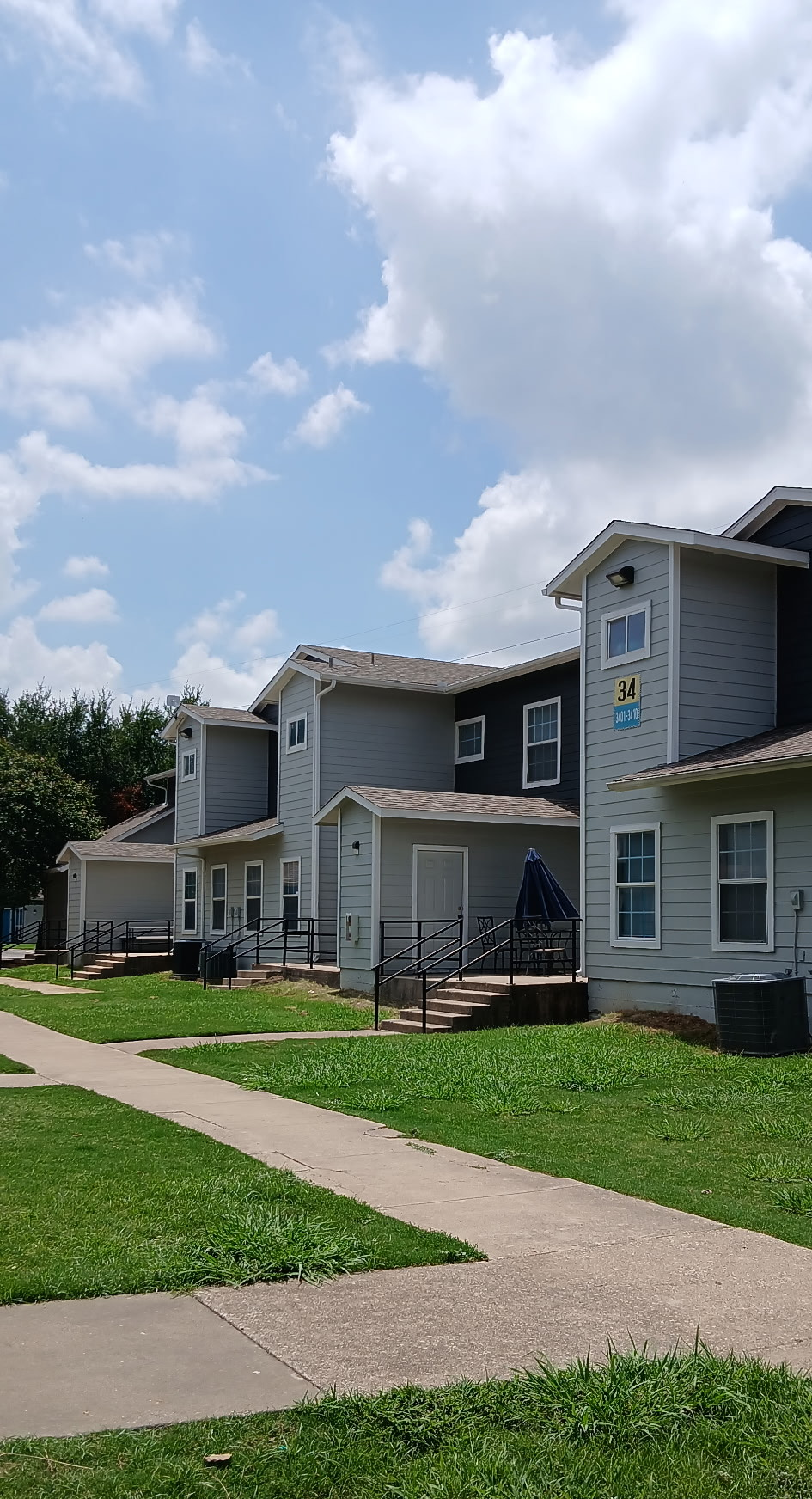 A row of houses with a sidewalk in front of them on a sunny day.