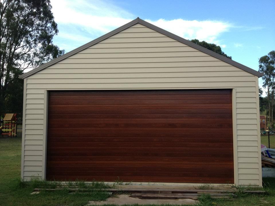 A White Garage With A Brown Garage Door — Austeel Sheds in Bowen, QLD