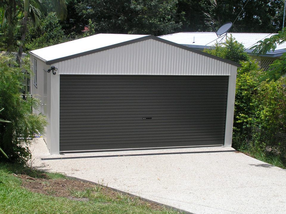 A Garage With A Gray Door And A White Roof — Austeel Sheds in Collinsville, QLD