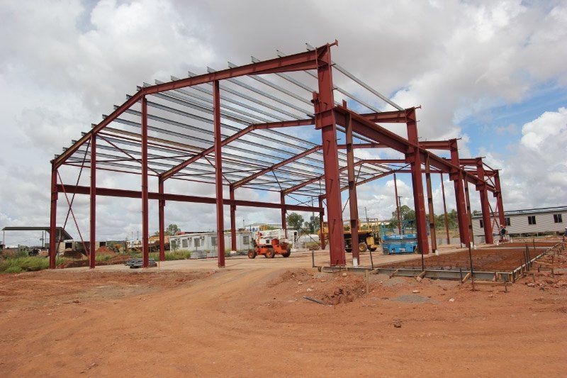 A Large Metal Structure Is Being Built In A Dirt Field — Austeel Sheds in Bowen, QLD